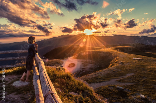 Girl watching a beautiful sunset in a peaceful and tranquil place, Mount Pizzoc summit, Veneto, Italy