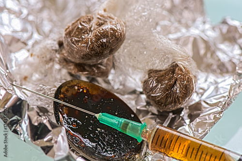 Wraps of brown drugs with a spoon and syringe on foil