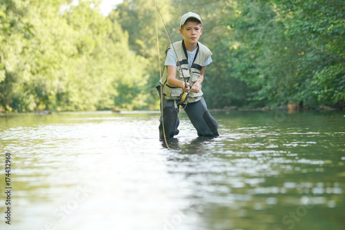Young boy fly-fishing in river