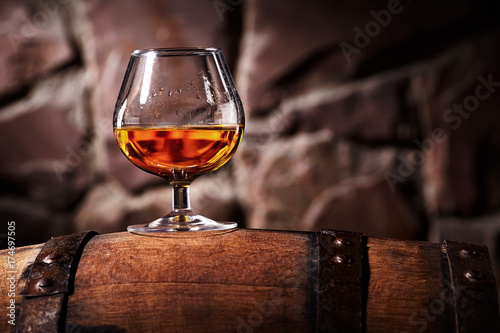 Glass of cognac on the old wooden barrel