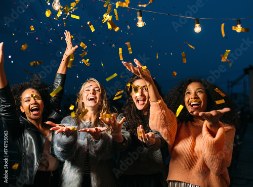 Happy women throwing confetti in the air. Friends celebrating outdoors.