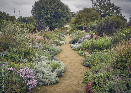 An informal gravel path through a large cottage garden with dovecote