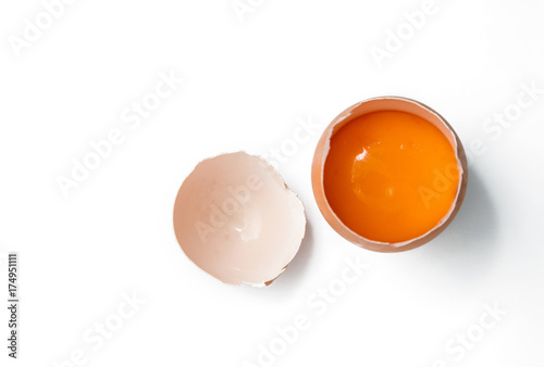 egg yolk in egg shell, cracked egg white isolated on white background