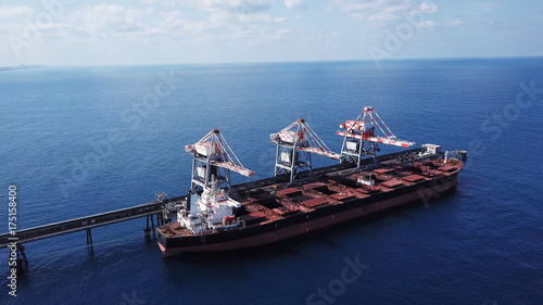 Large bulk carrier ship docking - Unloading coal ship by cranes on the power station dock