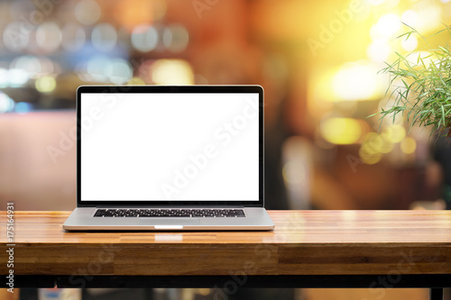 Laptop blank screen on wooden table in coffee shop morning sunshine background