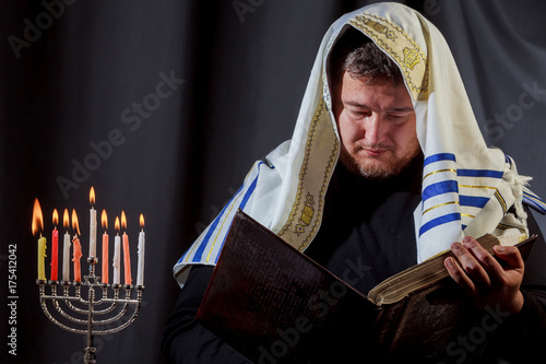 jewish man with beard lighting the candles of a menorah