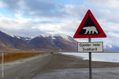 Polar bear warning sign in Svalbard, scenic arctic lansdscape. Beautiful clean nature, mountains, lake and road