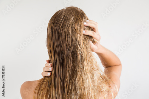 Woman touching her wet blonde hair after shower on the gray background. Before and after hair brushing with comb. Cares about a healthy and clean hair. Beauty salon concept.