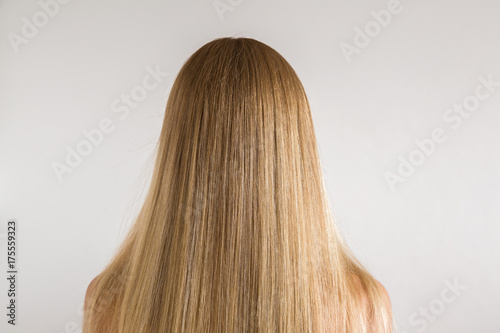 Woman's dry blonde hair after brushing with comb on the gray background. Cares about a healthy and clean hair. Beauty salon concept.