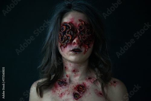 Girl with realistic sores and worms in her eyes. Creative halloween makeup.