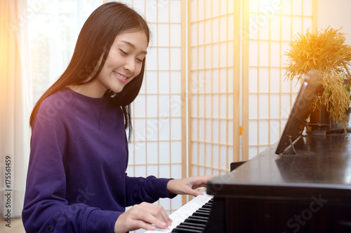 Lovely teen playing piano in the music room.