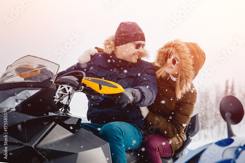 Snowmobile. A couple of girlfriends and a guy on a snowmobile laugh. Concept travel in winter.