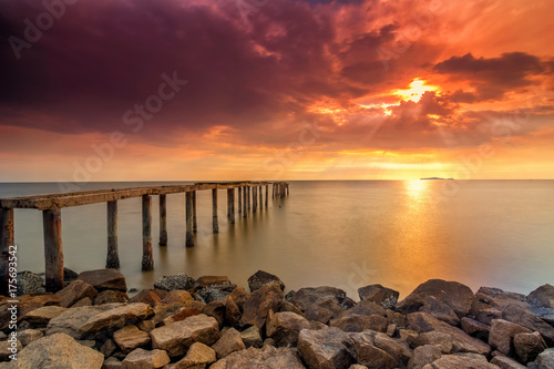 A long Exposure Picture Of abandoned old jetty with burning sunset as background