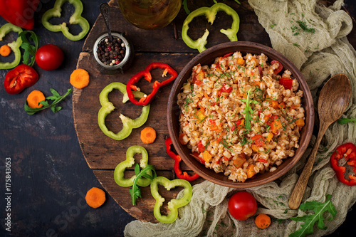 Vegetarian crumbly pearl barley porridge with vegetables in a dark background. Flat lay. Top view