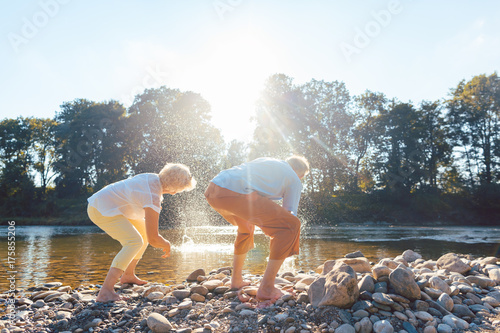 Two senior people enjoying retirement and simplicity while throwing stones into the river