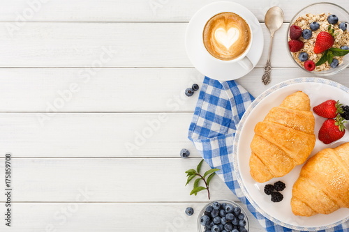 Continental breakfast with croissants and berries on white wood