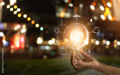 Hand holding light bulb in front of global, show the world's consumption with icons energy sources for renewable, Ecology concept. Elements of this image furnished by NASA.