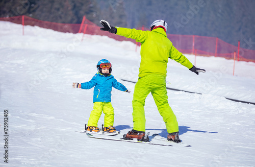 Instructor teaching little boy to ski