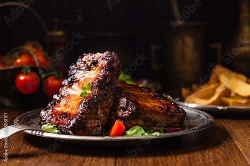 Roasted ribs, served on an old plate. Dark or balck background.