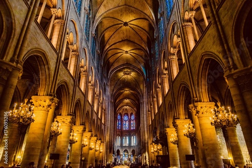 mystical image of the interior of Notre Dame cathedral In Paris with candles of lit faithful illuminated by colored stained glass windows