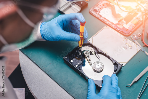 The abstract image of the technician repairing inside of hard disk drive by screwdriver in the lab. the concept of data, hardware, technician and technology.