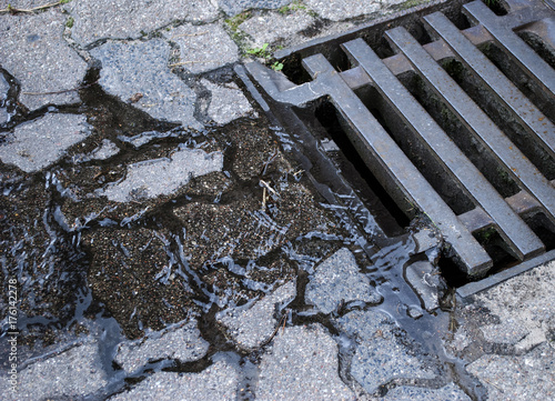 Wasser / Regenwasser fliesst in Kanalisation durch Gullideckel