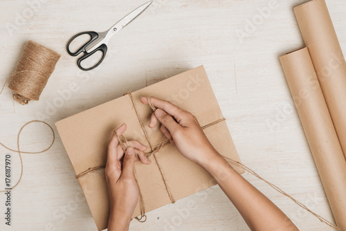 Man wrapping gift. A parcel wrapped in brown paper and tied with rough twine