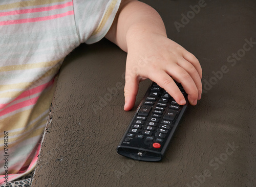 Dziecko zmienia programy na telewizorze pilotem, dłonie i pilot.