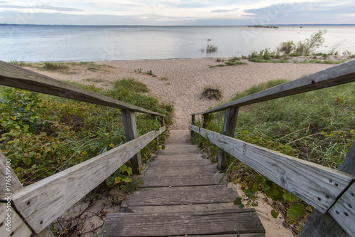 Summer Vacation Background. Long wooden staircase leads to a wide sandy beach with the blue waters of Lake Michigan at the horizon. Shot wide angle with copy space at the background.