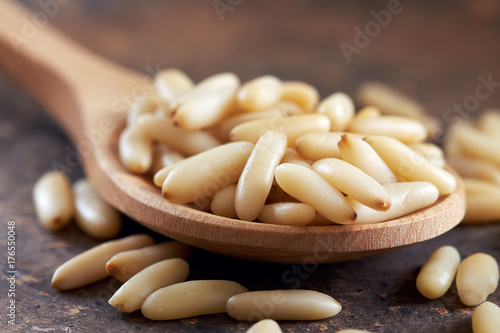 Raw pine nuts in wooden spoon on rustic background