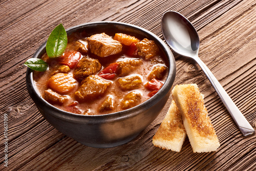 Goulash, beef stew with herbs on wooden background