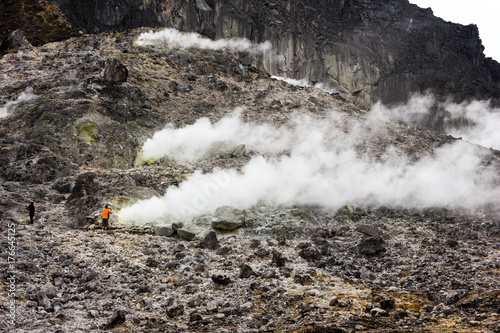 Tourists dangerous close to a steaming volcanic vent belching out toxic gas