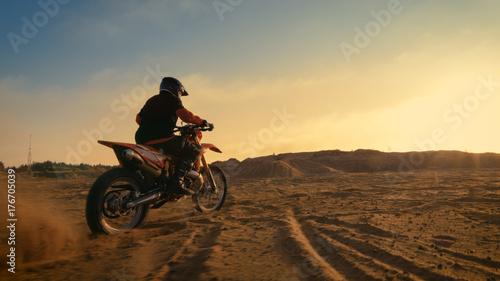 Shot of the Professional Motocross Driver Riding on His FMX Motorcycle on the Extreme Off-Road Terrain Track.