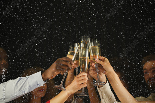 Group of young people celebrating new year with champagne at night club