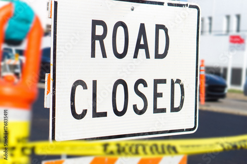 Road closed sign and block in a busy city street in the middle of traffic. Roadblock in a highway.