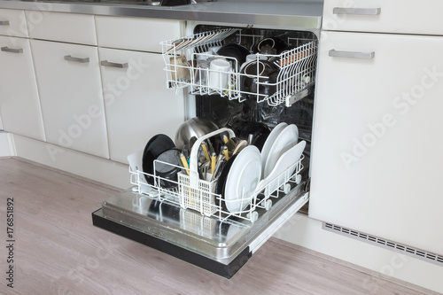 Open dishwasher with clean plates, cups and dishes