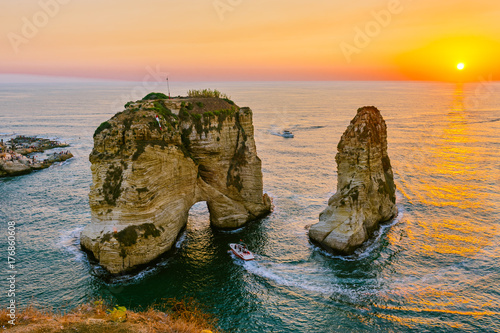 Beautiful sunset on Raouche, Pigeons' Rock. In Beirut, Lebanon.Sun and Stones are reflected in water.dense clouds in the sky.