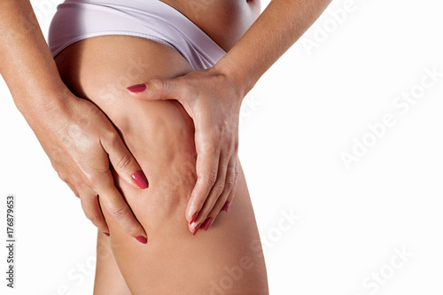 Woman squeezing her thigh to show cellulite
