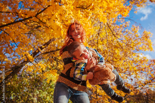 Happy mother and her little son walking and having fun in autumn forest.