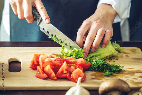 The chef in black apron cuts vegetables. Concept of eco-friendly products for cooking