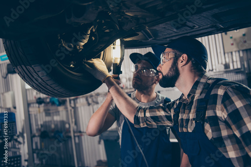 Car care, upgrading, automotive, industry, team building, team work, friends, friendship, oneness, help, colleagues professionals in special blue safety overalls uniform, protective spectacles