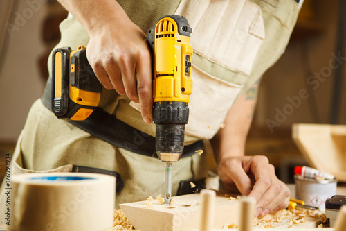 Wood boring drill in hand drilling hole in wooden bar