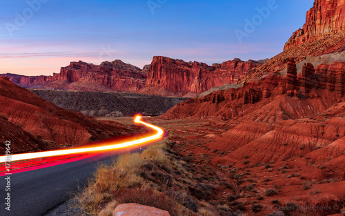 A trail of automobile lights leads the way through the canyons of Capitol Reef National Park, Utah