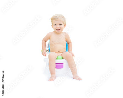 Infant boy, white caucasian smiling and sitting on the potty with white background. 