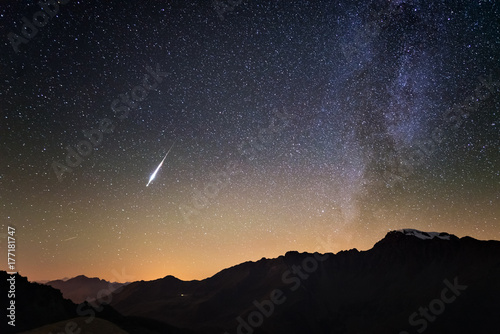Milky Way and starry sky from high up on the Alps. Real Christmas comet in the sky. Majestic high mountain range with glacier and snow.