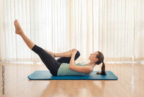 Woman on yoga mat doing leg stretch. 