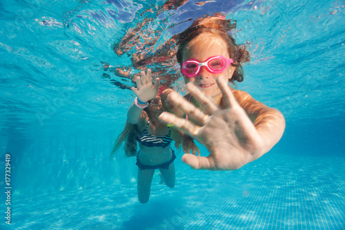 Two little girls diving underwater in pool