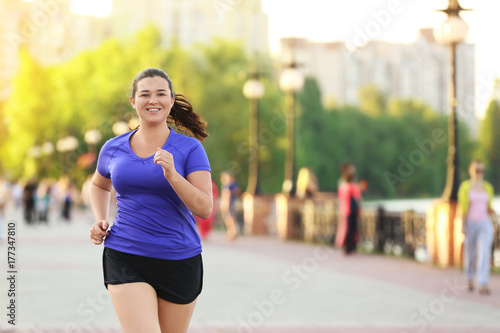 Overweight young woman jogging in the street. Weight loss concept