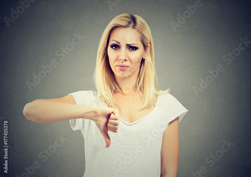 Woman giving thumb down gesture looking with negative expression and disapproval