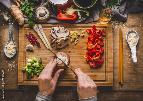 Vegetarian stir fry cooking preparation. Women female hands cut vegetables for stir fry on kitchen table background with ingredients, top view. Asian food , Chinese or Thai cuisine concept